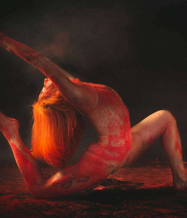 Person doing an energetic yoga pose against a dark background.